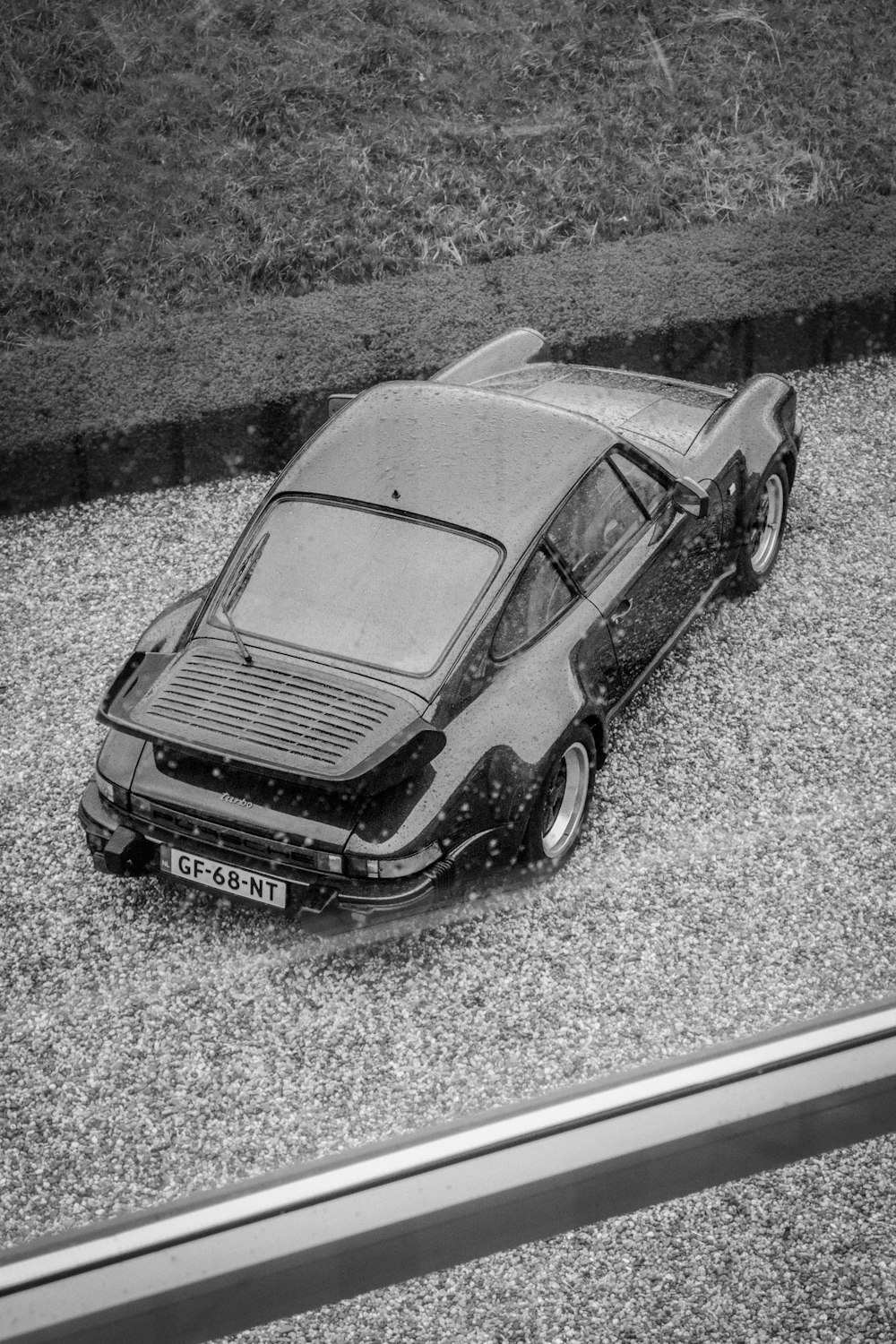 a black and white photo of a car parked in gravel