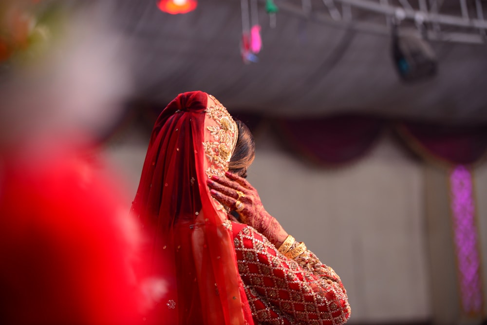 a woman in a red sari covering her face