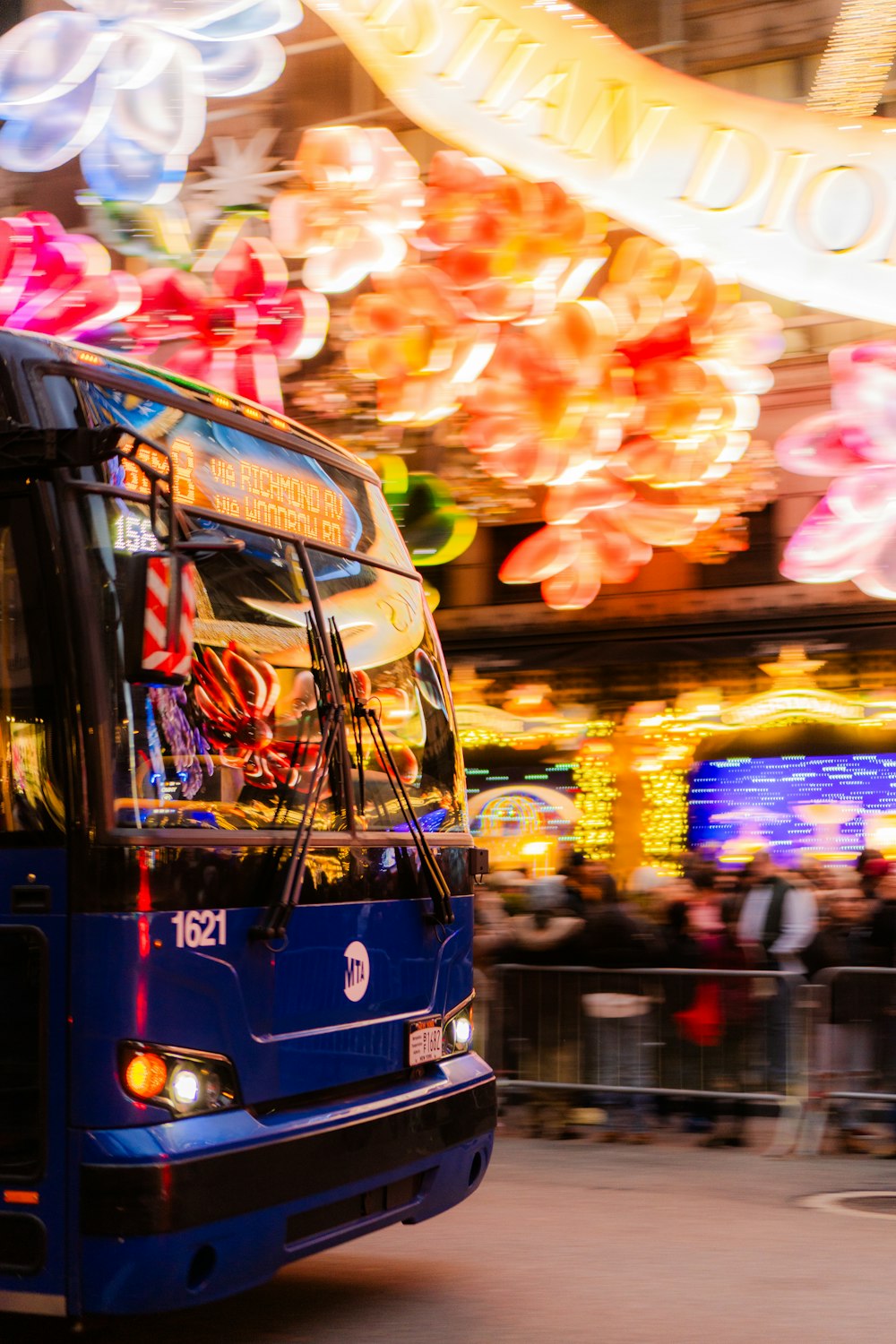 Ein blauer Bus, der eine Straße neben einem Karneval entlangfährt