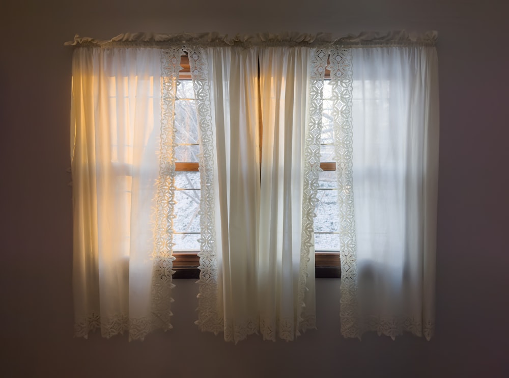 a window with a white curtain and a window sill