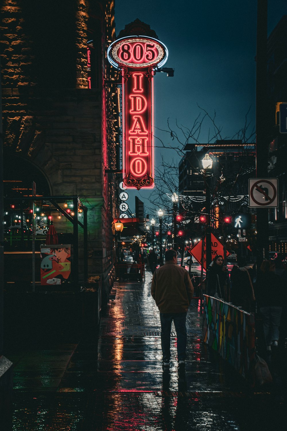 a man walking down a street next to a neon sign