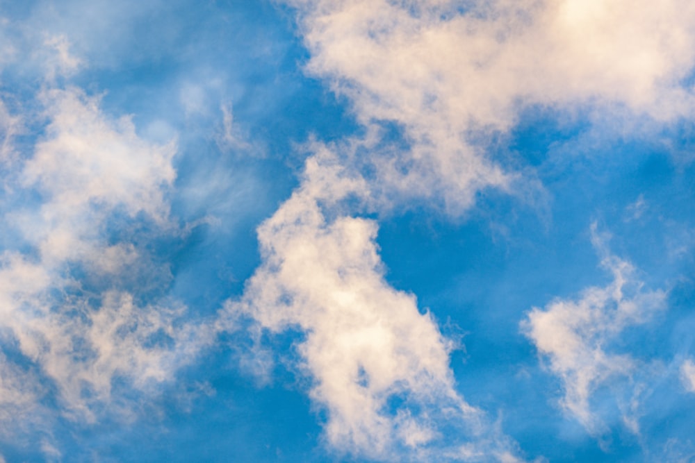 a plane flying through a cloudy blue sky