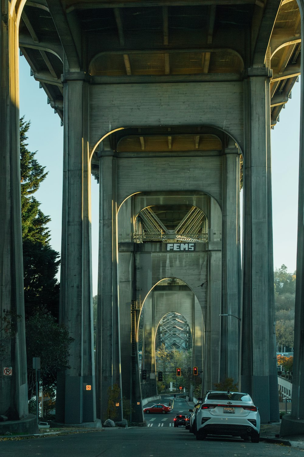 two cars are parked under a large bridge