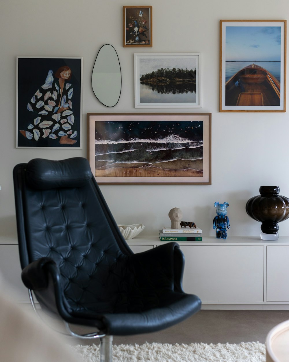 una silla negra sentada en una sala de estar junto a una alfombra blanca