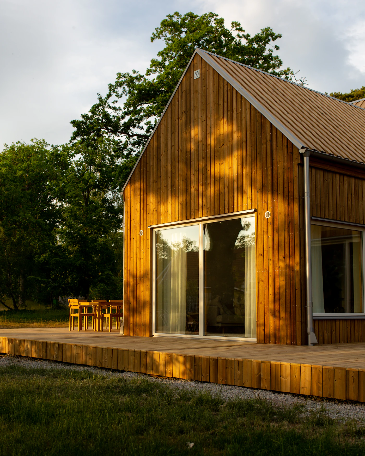 Wooden barndominium style home with covered deck and patio in a rural setting
