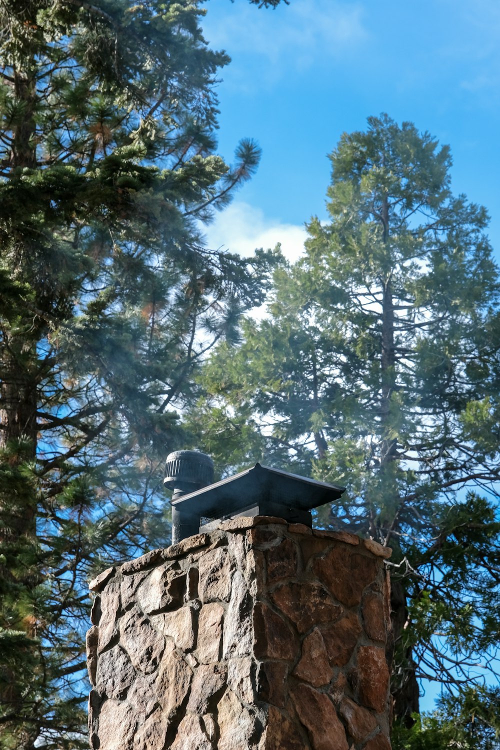 une cheminée en pierre d’où sort de la fumée