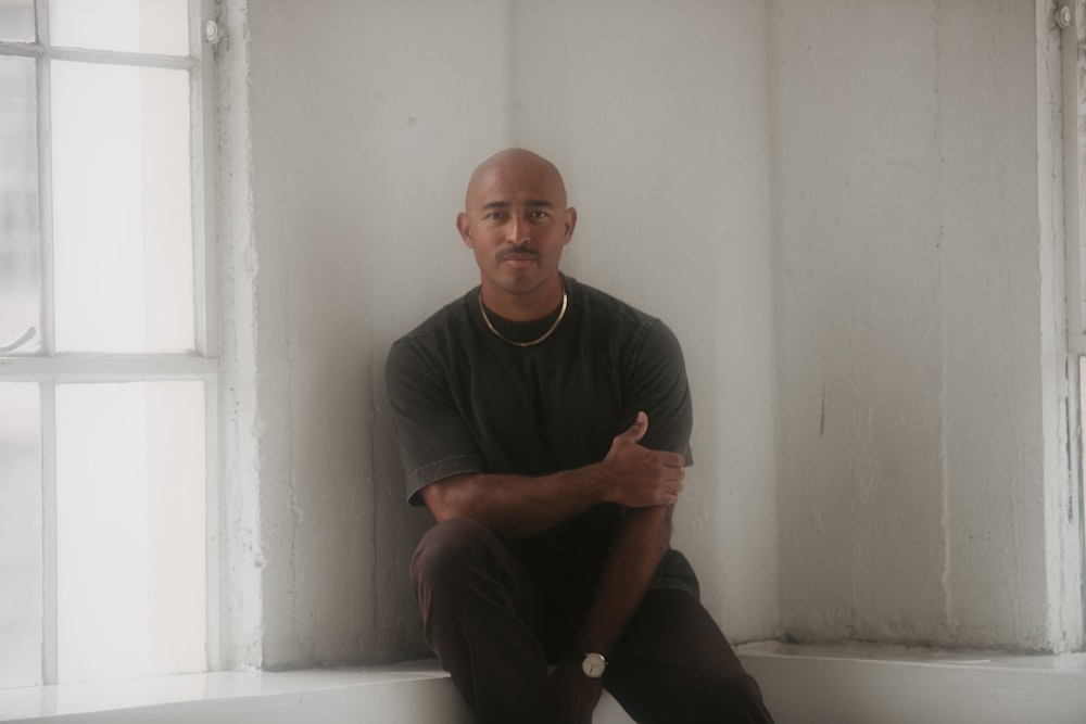 a man sitting on a window sill in front of a window