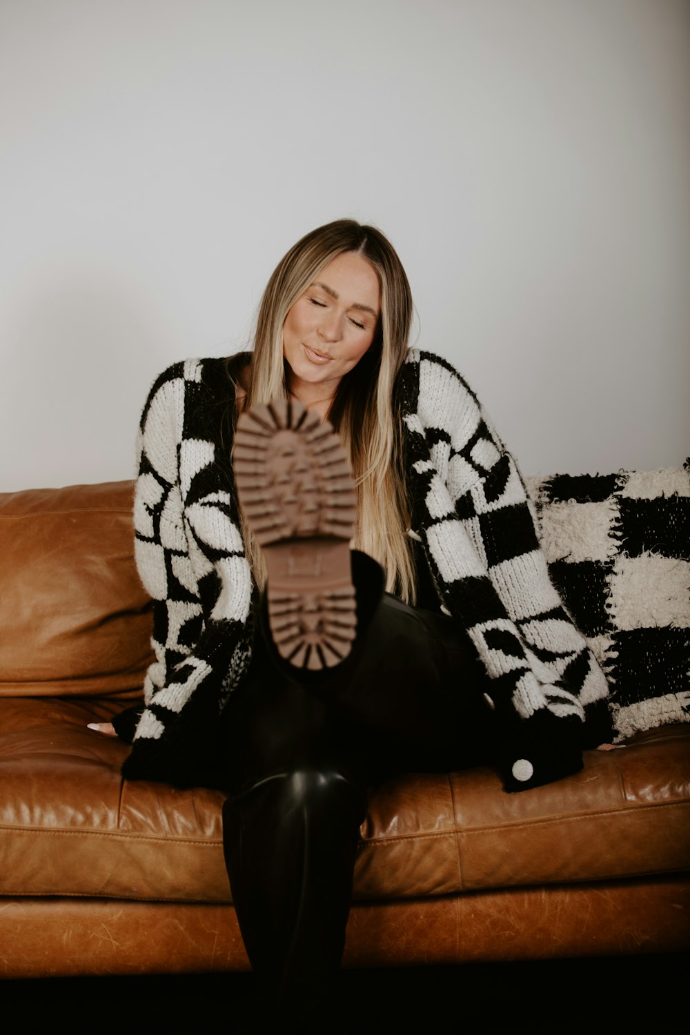 a woman sitting on top of a brown leather couch