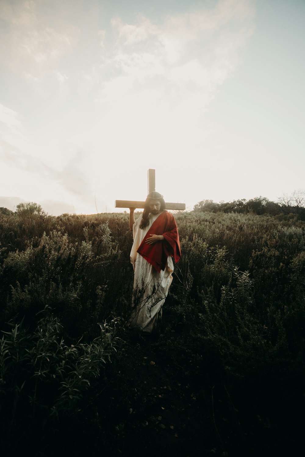 a person in a field with a cross in the background