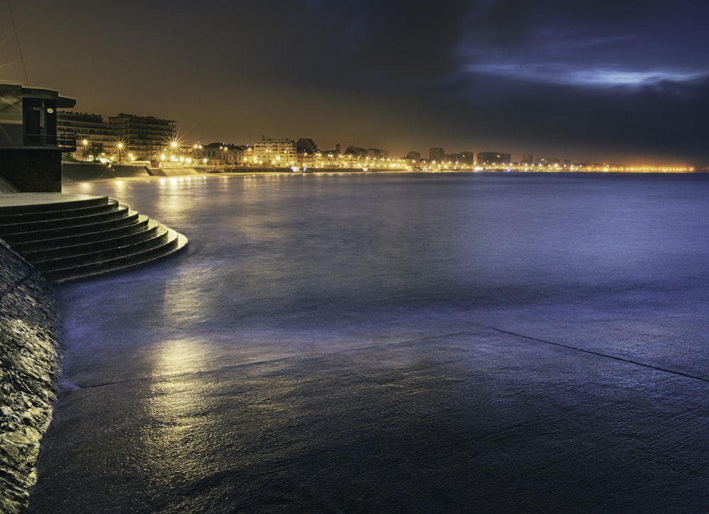 a body of water at night with a city in the background