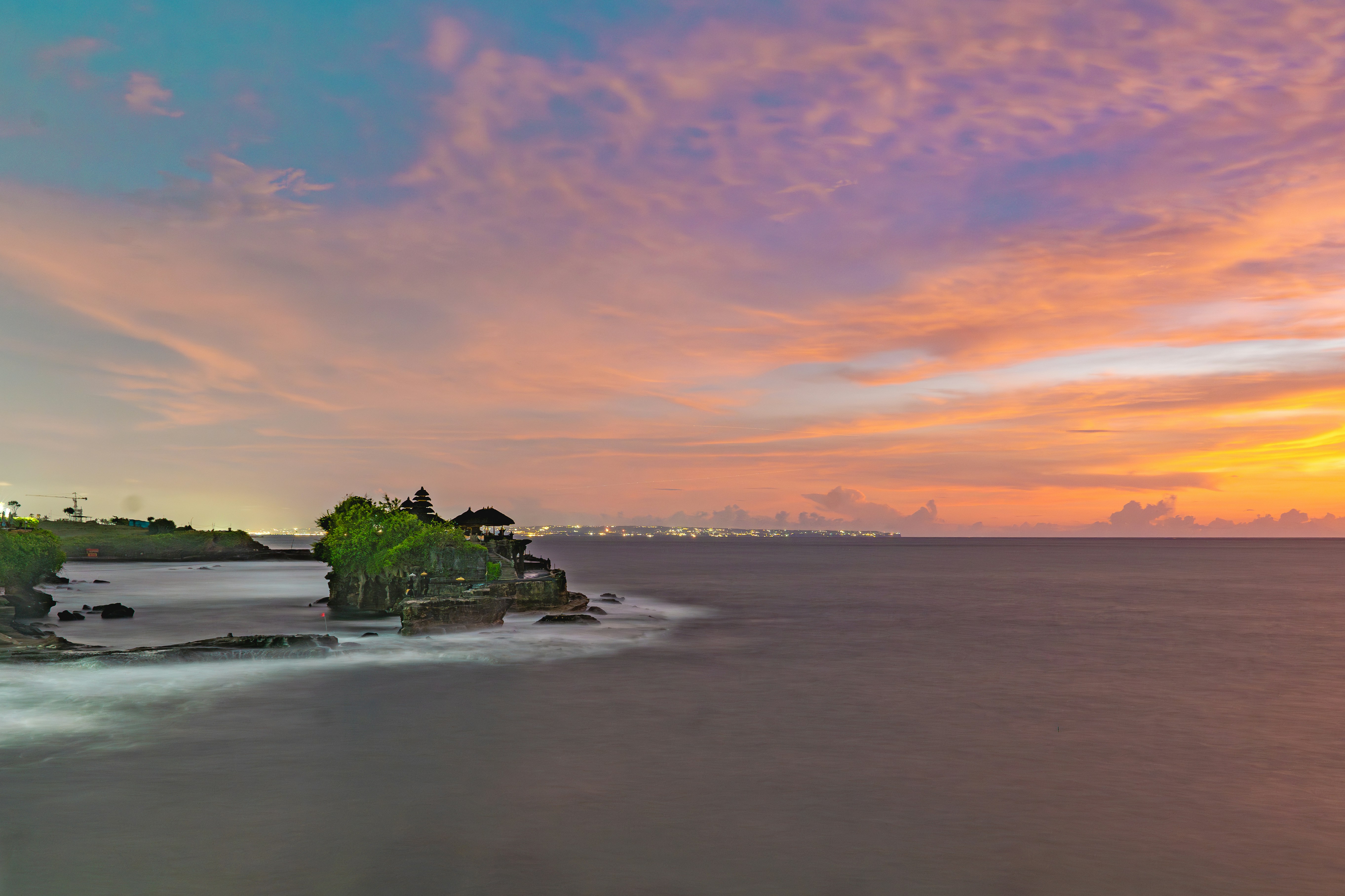 a beautiful sunset over the ocean with a small island in the middle of the water