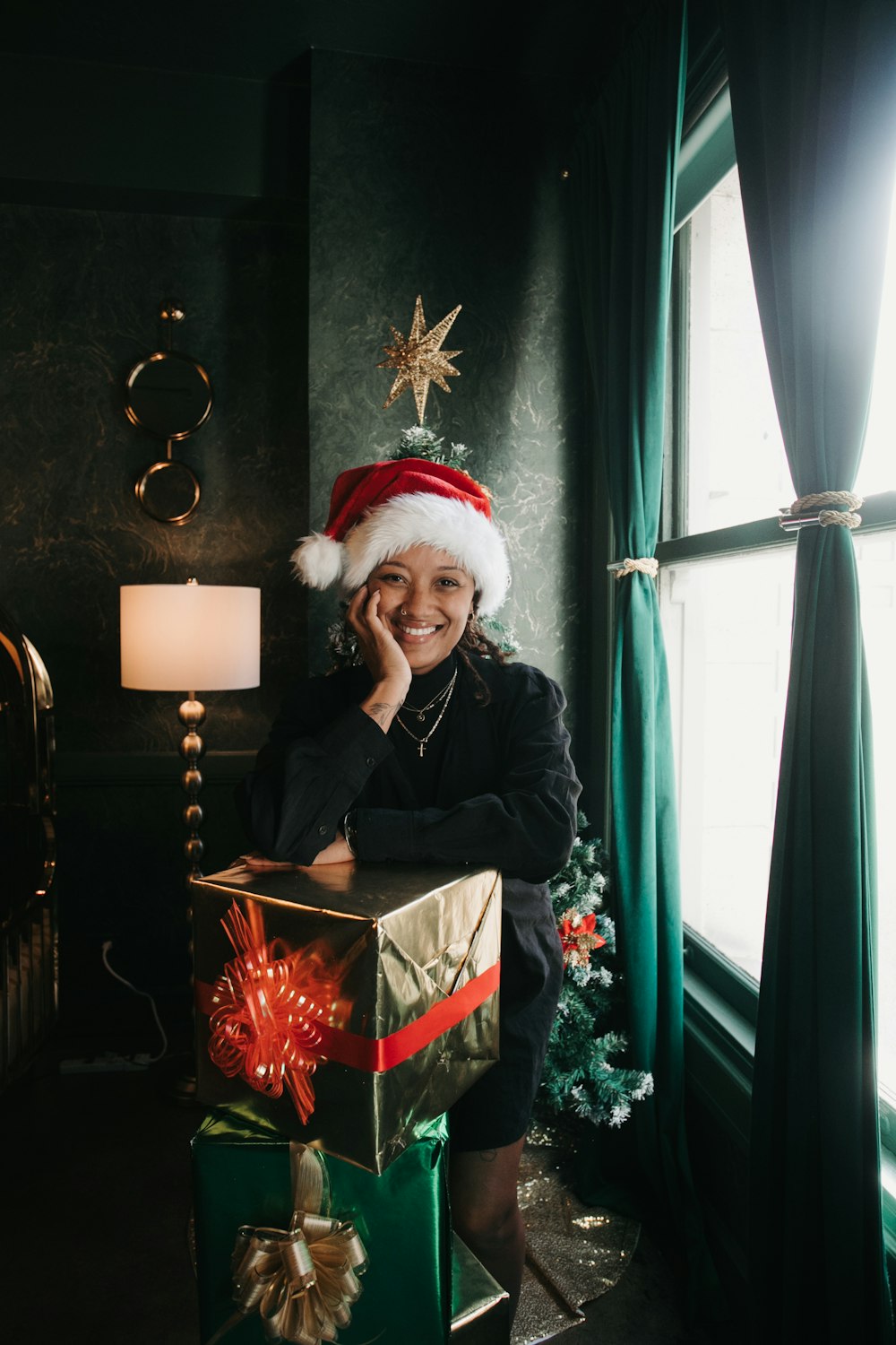 산타 모자를 쓴 여성이 크리스마스 선물 옆에 앉아 있다