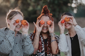 a group of women holding up oranges to their eyes