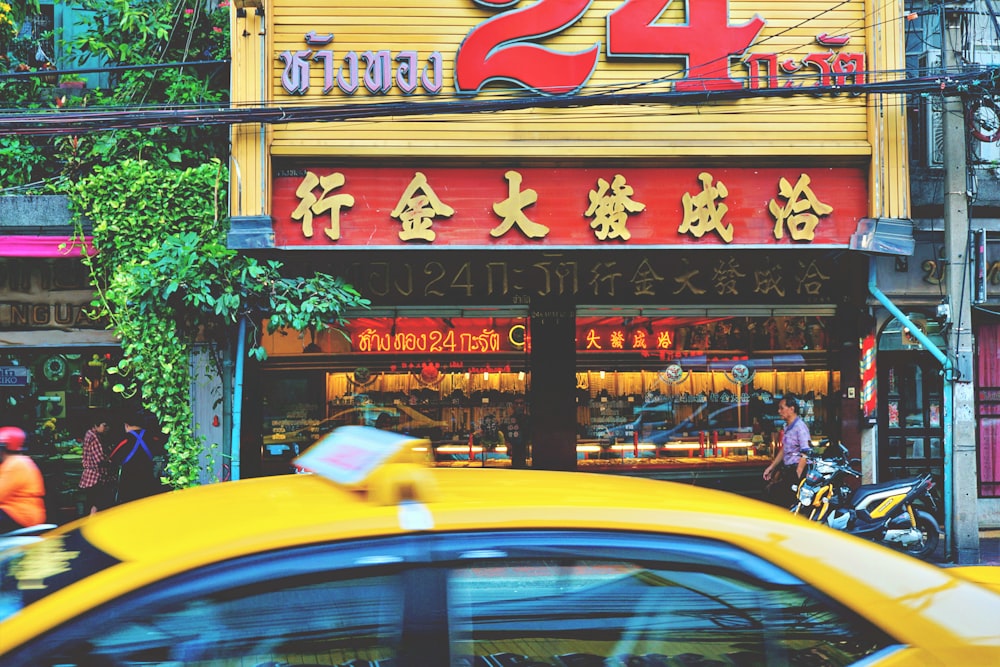 a yellow taxi driving past a store front