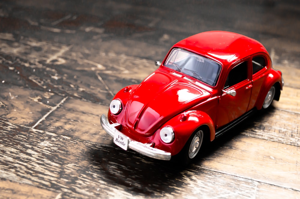 a red toy car sitting on top of a wooden floor