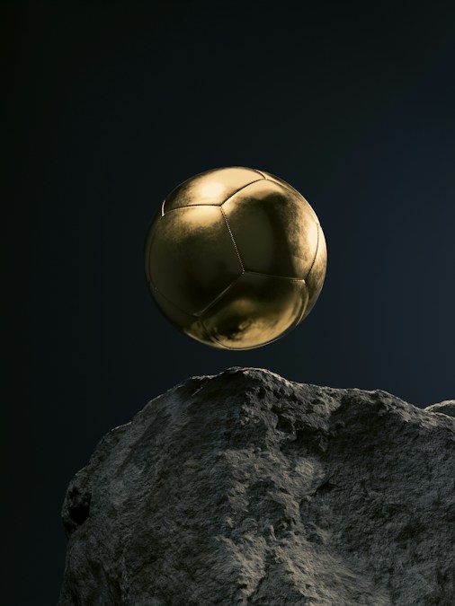 Un ballon de football doré suspendu au-dessus d'un rocher sur fond sombre, image d'illustration du Ballon d'Or 2026