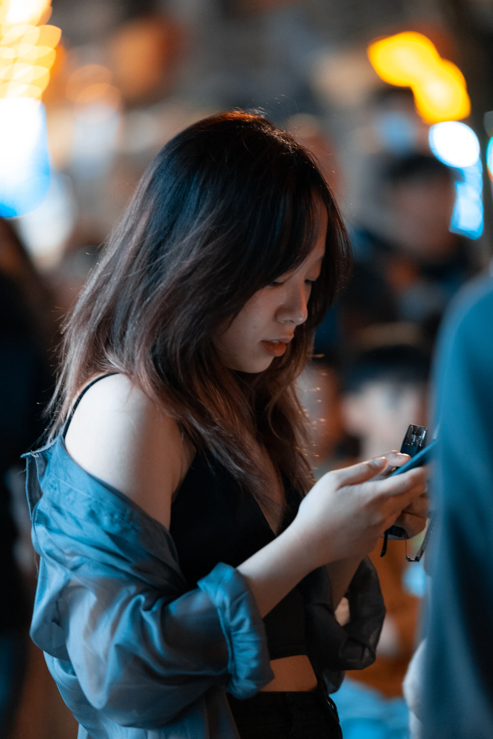 A woman in a blue top looking at her cell phone