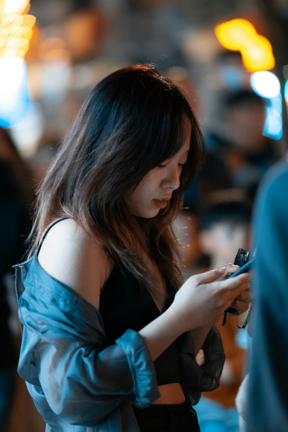 a woman in a blue top is looking at her cell phone