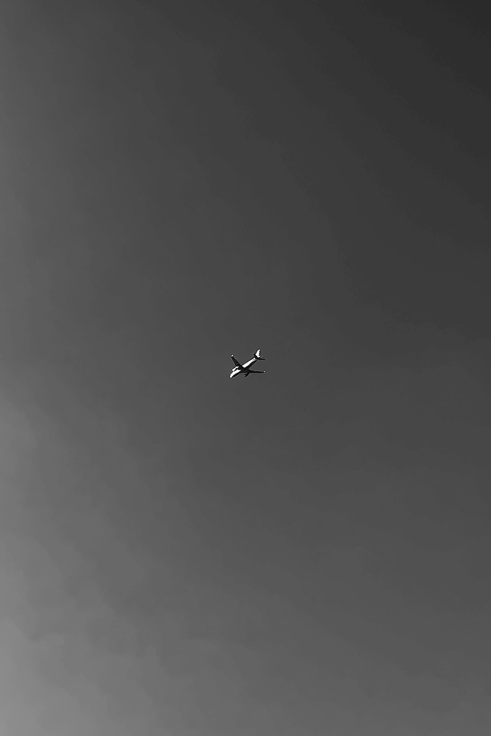 a black and white photo of an airplane in the sky