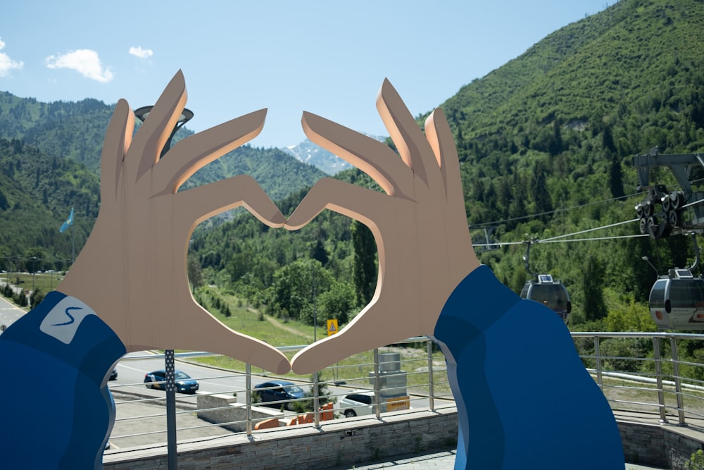 a pair of hands making a heart shape with mountains in the background