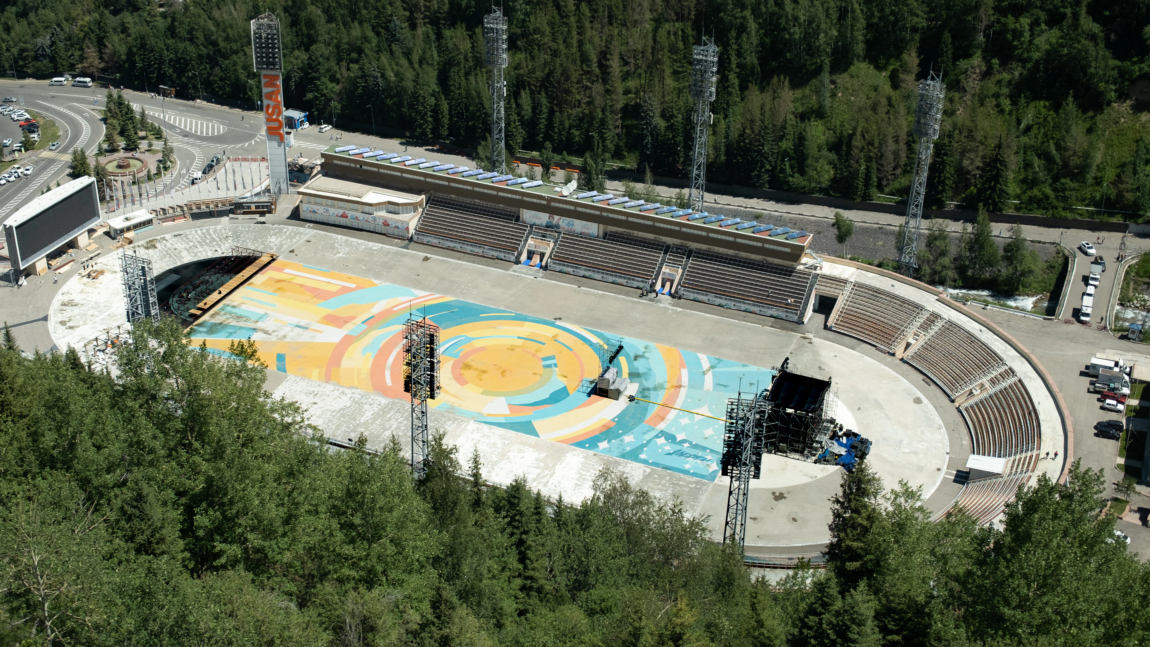 The Medeu skating rink's painted circular mural spreads across the ice below forested slopes.