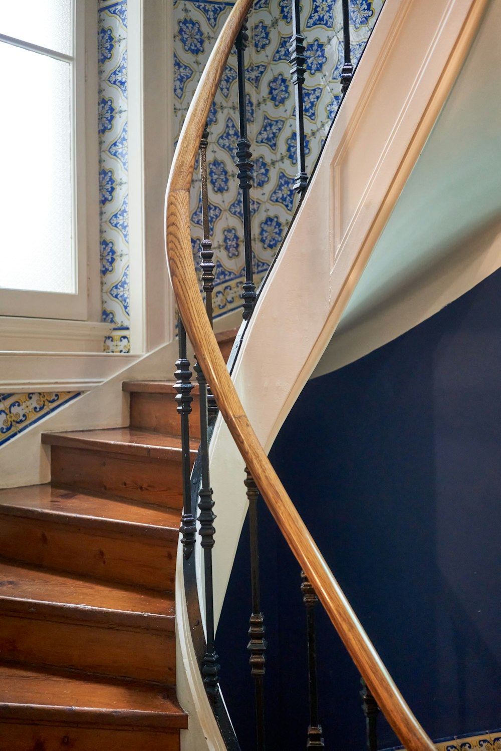 a spiral staircase in a home with blue and white wallpaper