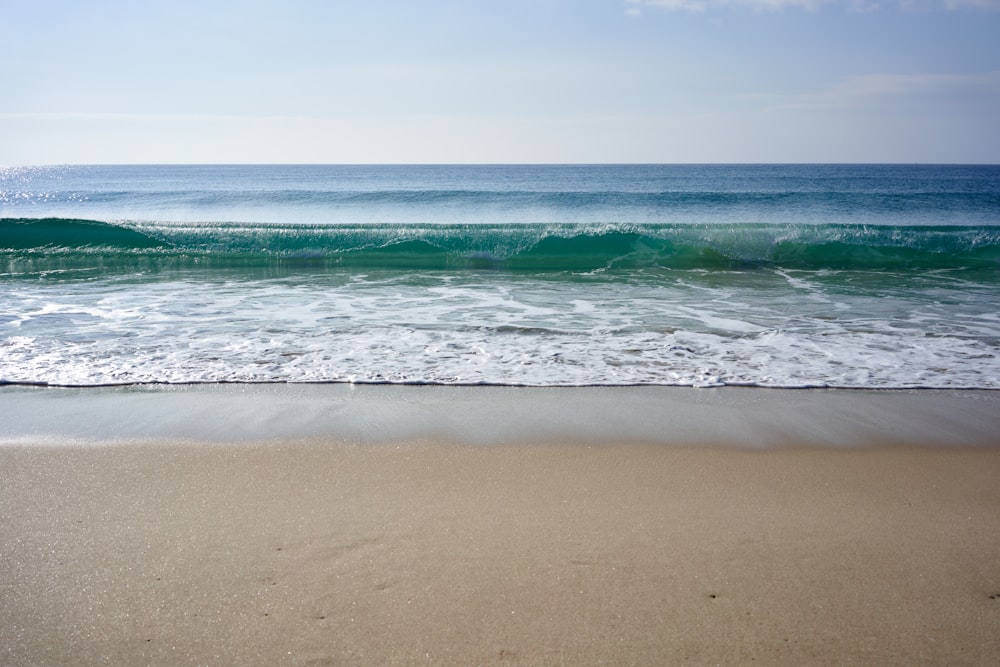 a beach with a wave coming in to shore