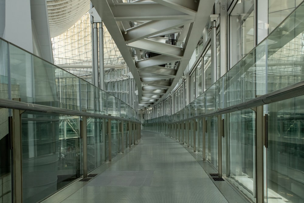 un long couloir avec des murs en verre et des balustrades en métal