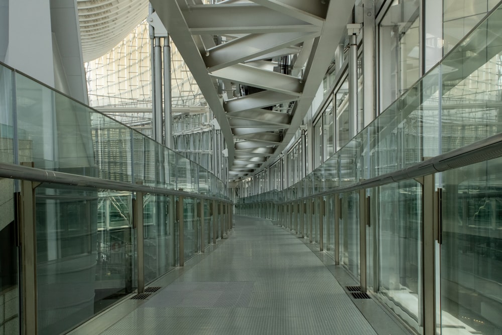 Un largo pasillo con paredes de vidrio y barandillas metálicas