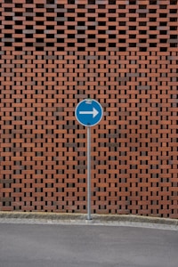 a blue street sign sitting next to a brick wall