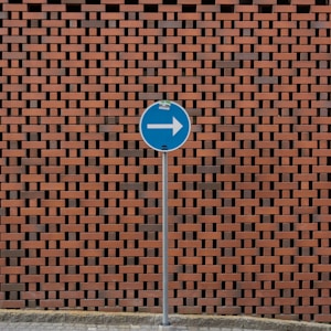 a blue street sign sitting next to a brick wall