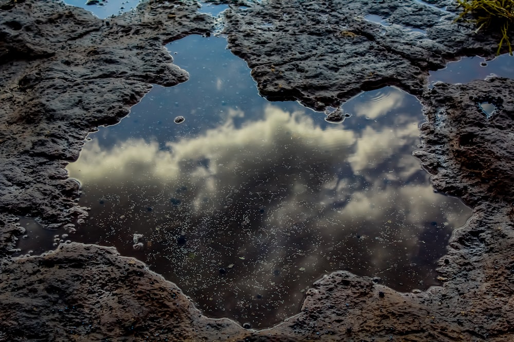 a reflection of clouds in a puddle of water