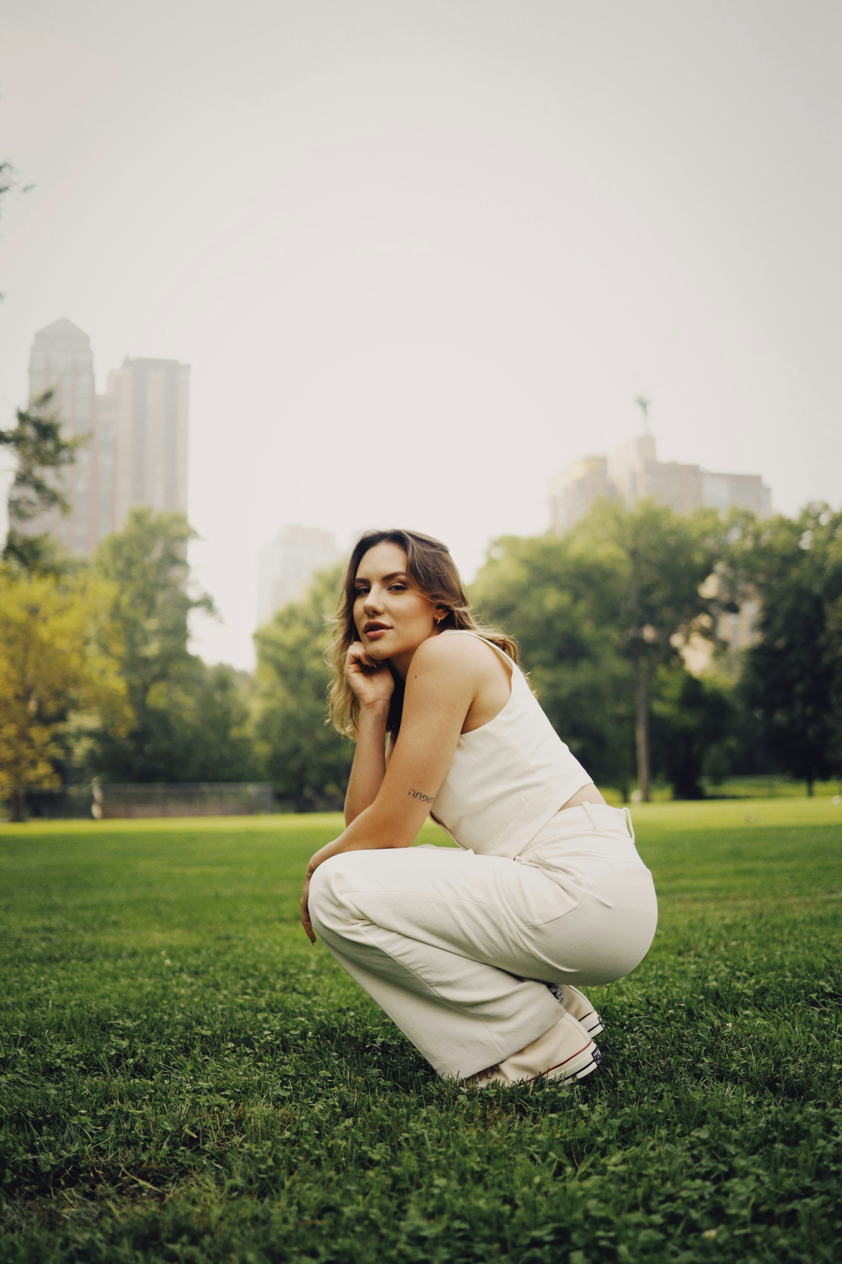 A woman kneeling in the grass in a park photo – Free Central park Image ...