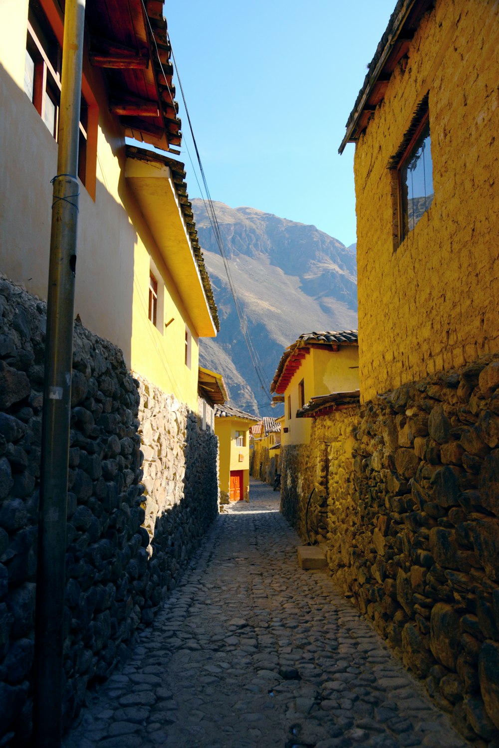 a cobblestone street in a village with mountains in the background