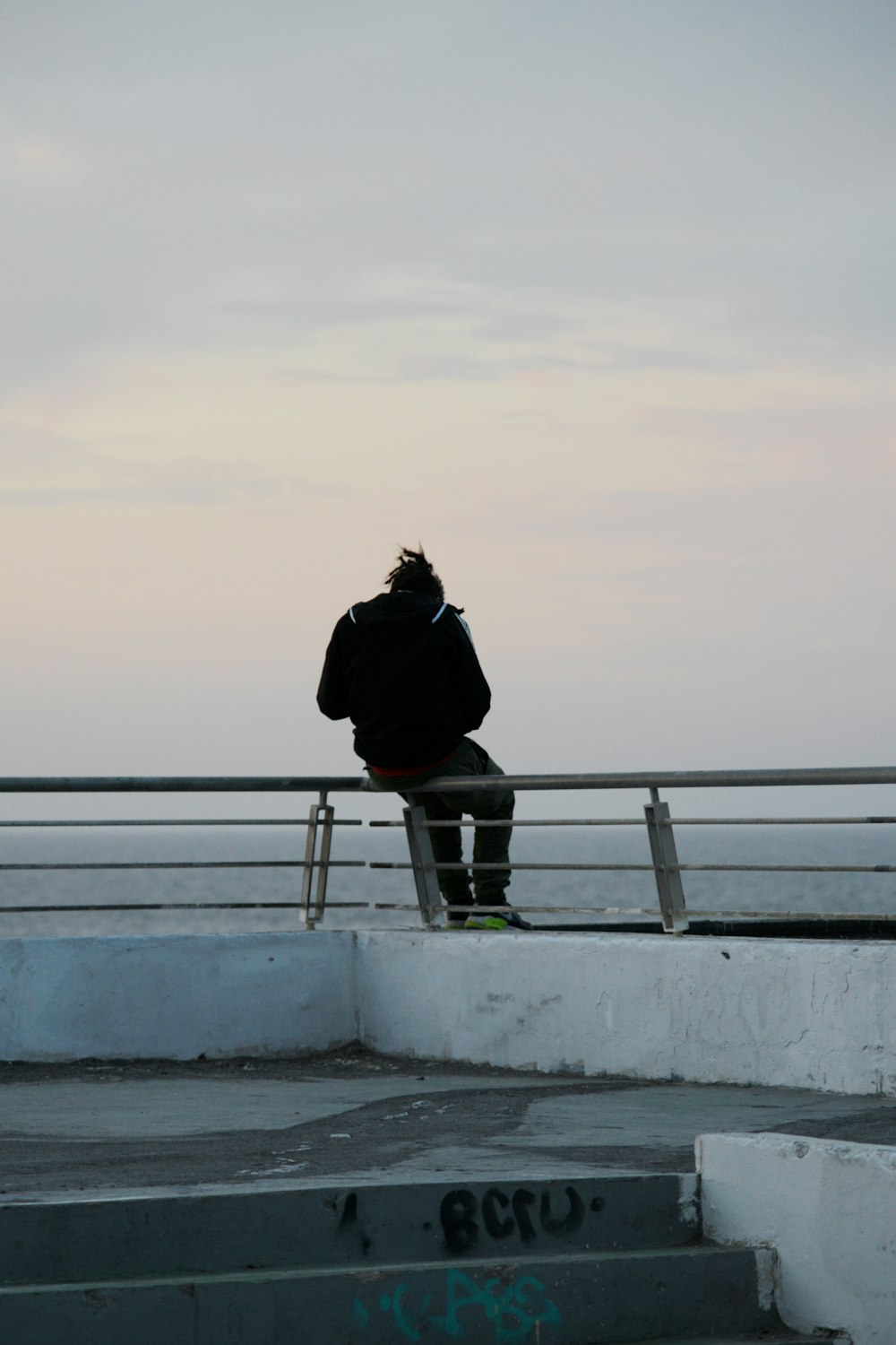 a man sitting on top of a metal rail