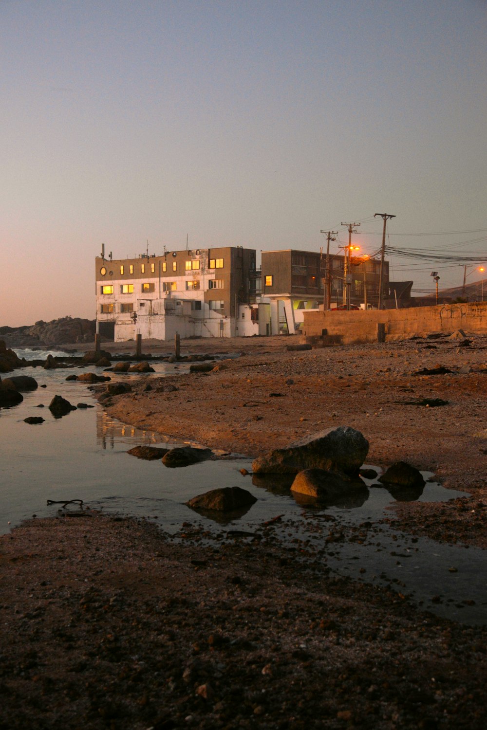 a building sitting on top of a beach next to a body of water