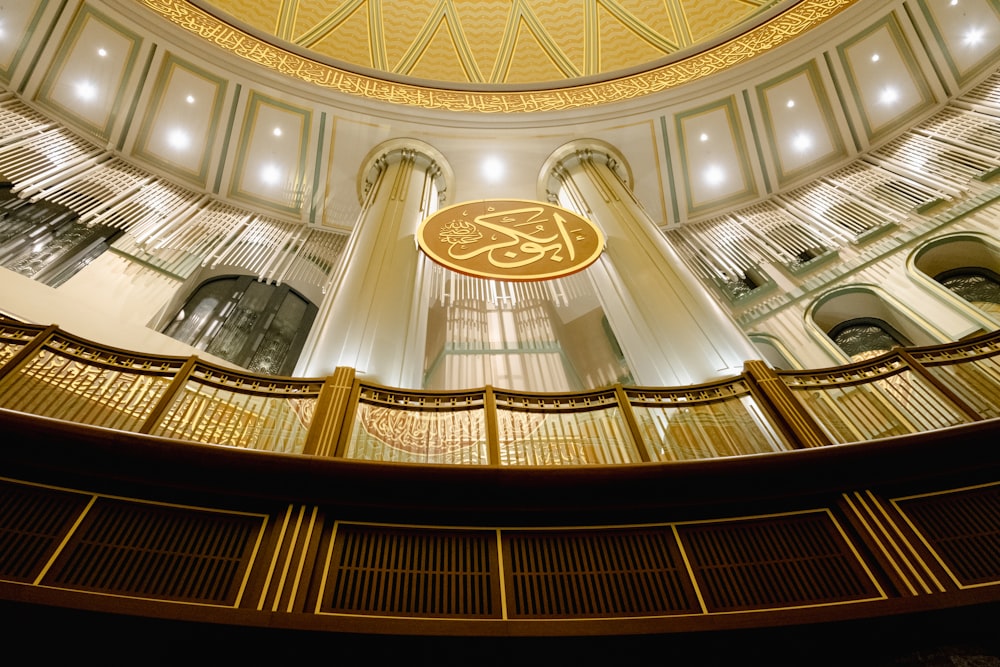un bâtiment circulaire avec une enseigne dorée et blanche accrochée au plafond