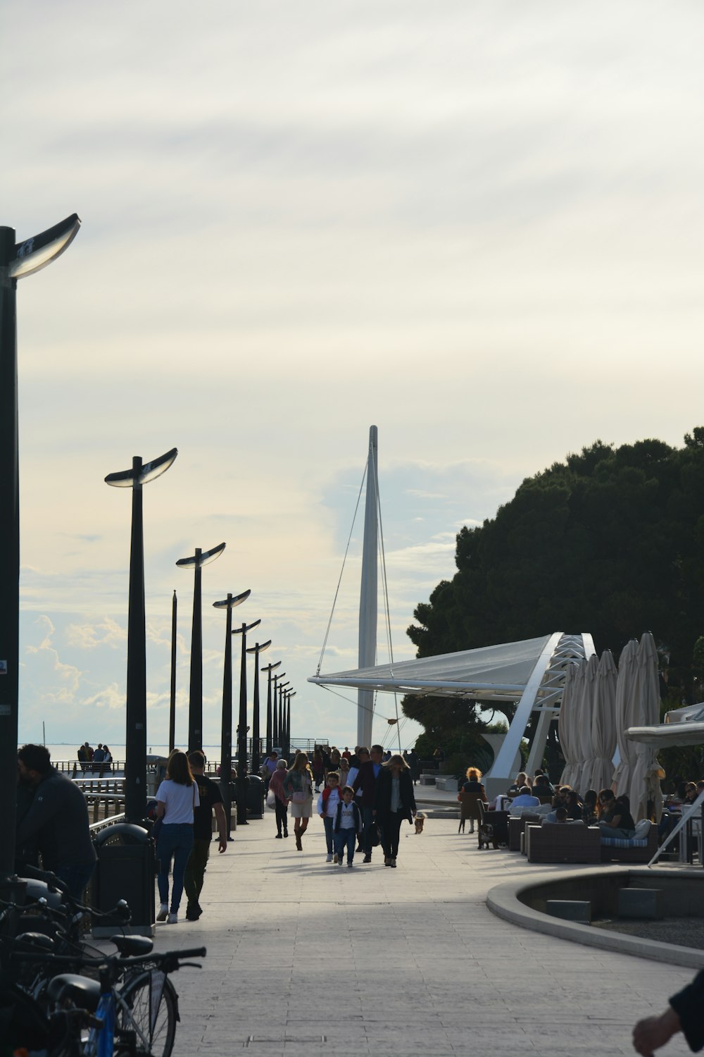 a group of people walking down a street next to tall poles