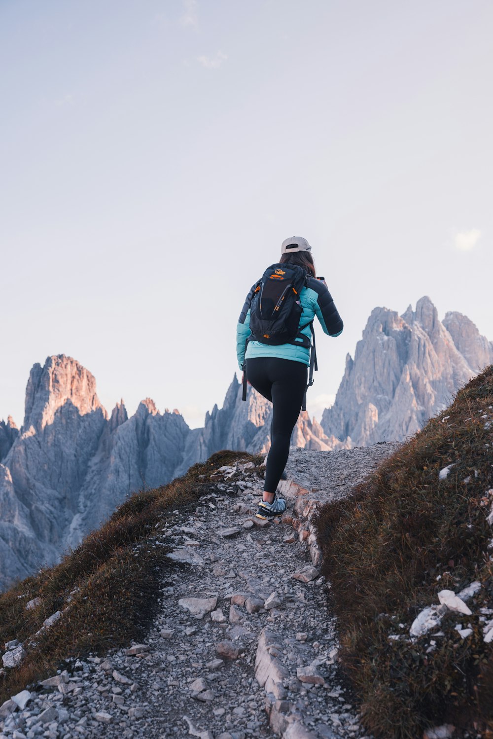 a woman hiking up a rocky trail in the mountains