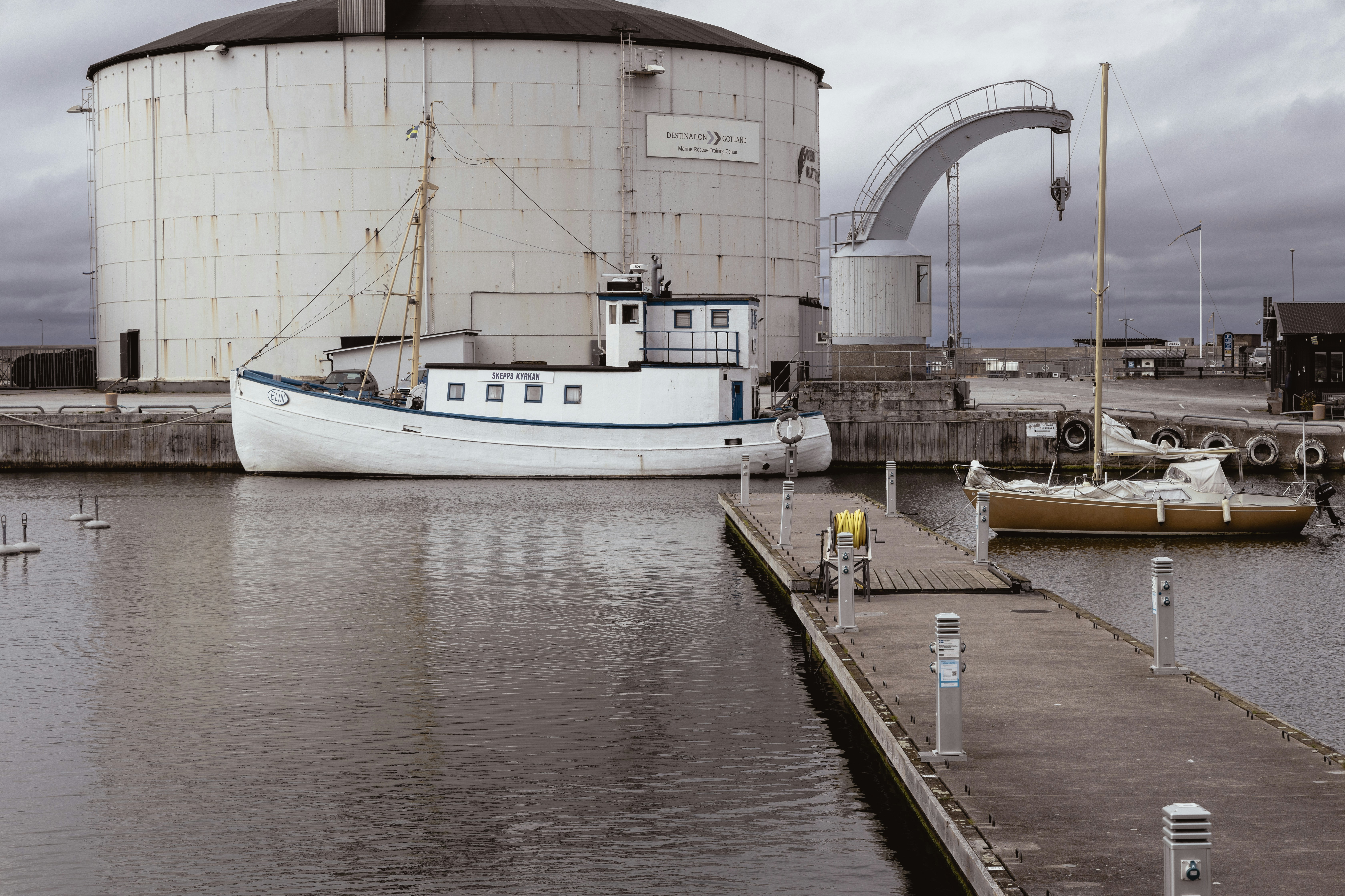 Bateau amarré dans le port de Visby devant un bâtiment historique en pierre.