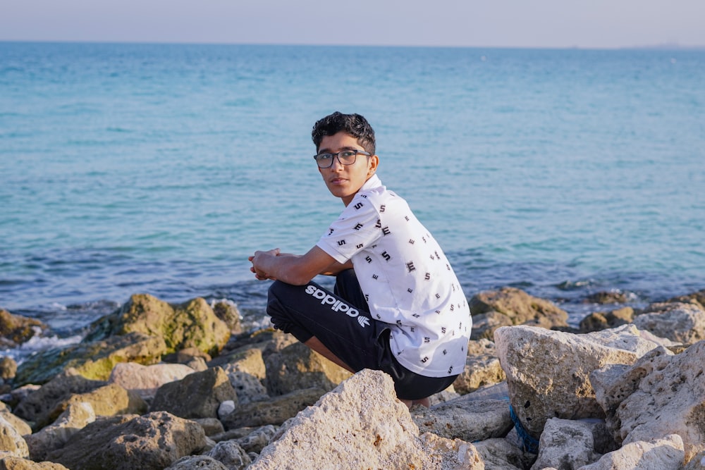 a man sitting on a rock near the ocean