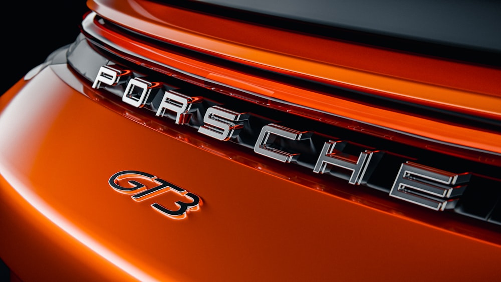 a close up of the emblem on an orange sports car