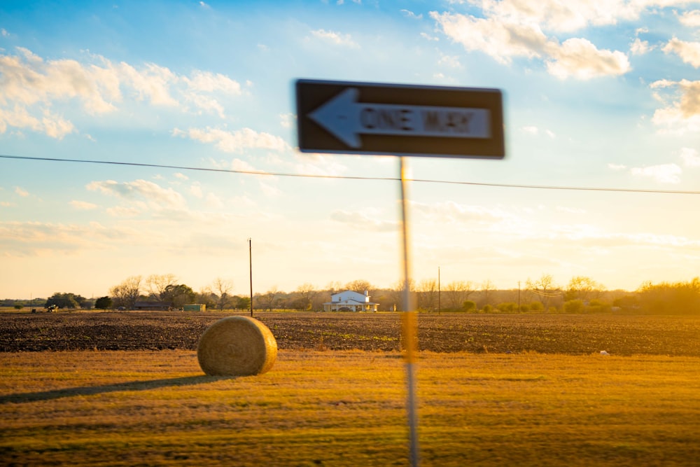 a field with a hay bale and a road sign