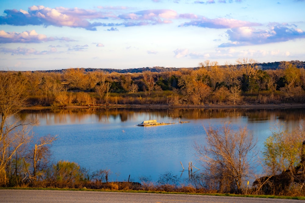 a small boat floating on top of a lake surrounded by trees