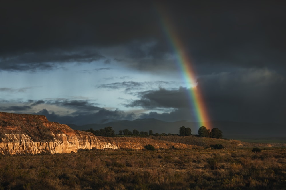 a rainbow shines in the sky over a mountain