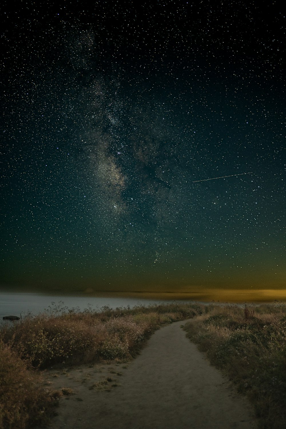 a path leading to the ocean under a night sky