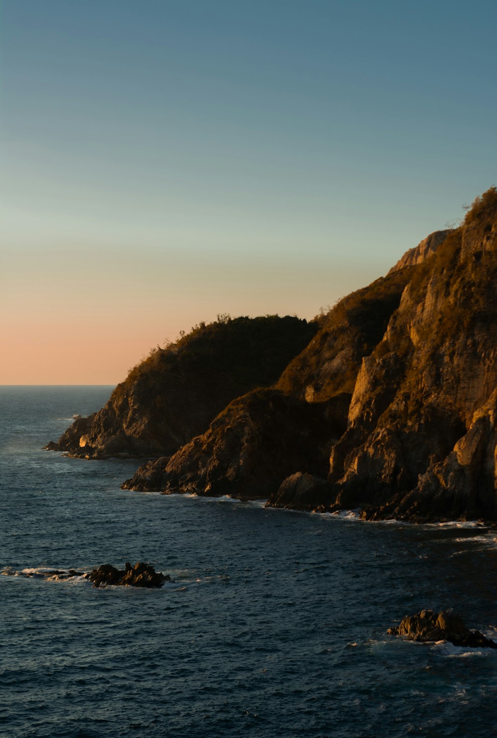 a large body of water next to a rocky cliff