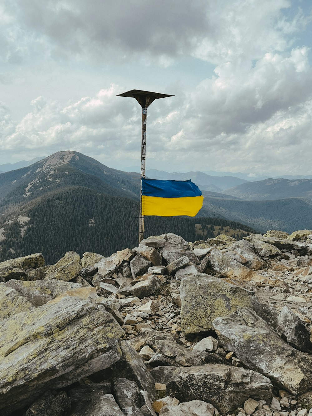 una bandera en la cima de una montaña con un fondo de cielo