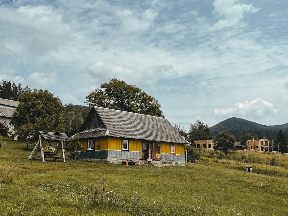 a small yellow house sitting on top of a lush green field