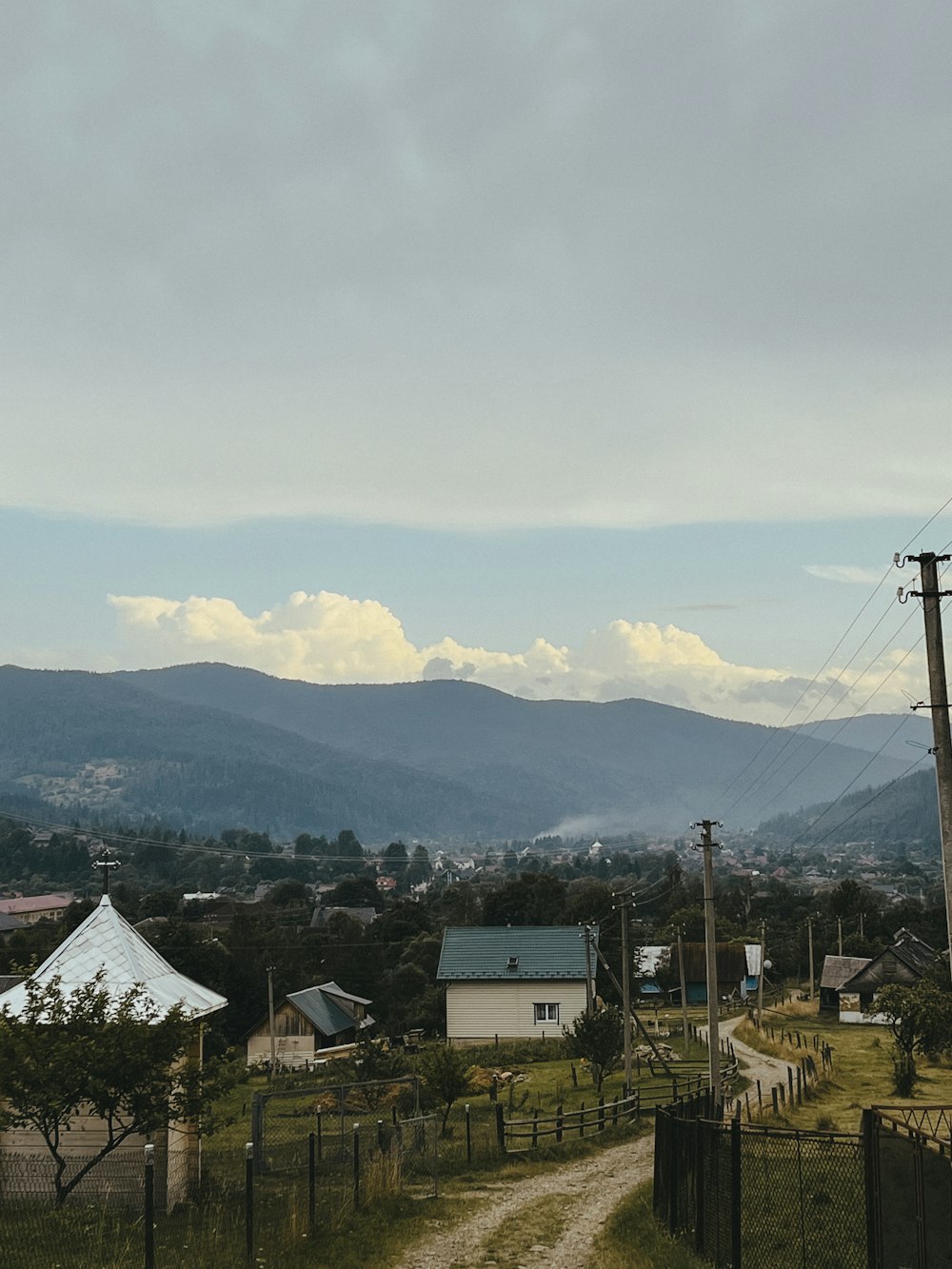 a dirt road in a rural area with mountains in the background